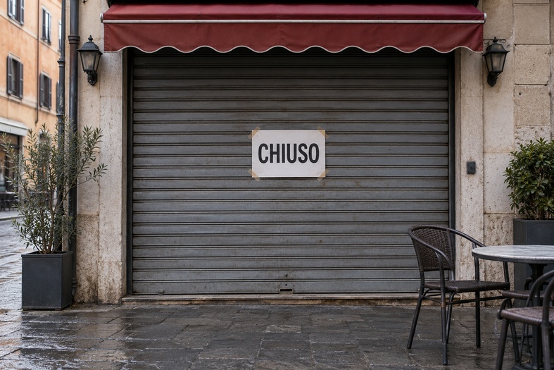 Serranda abbassata di un bar con un cartello «CHIUSO» affisso al centro.