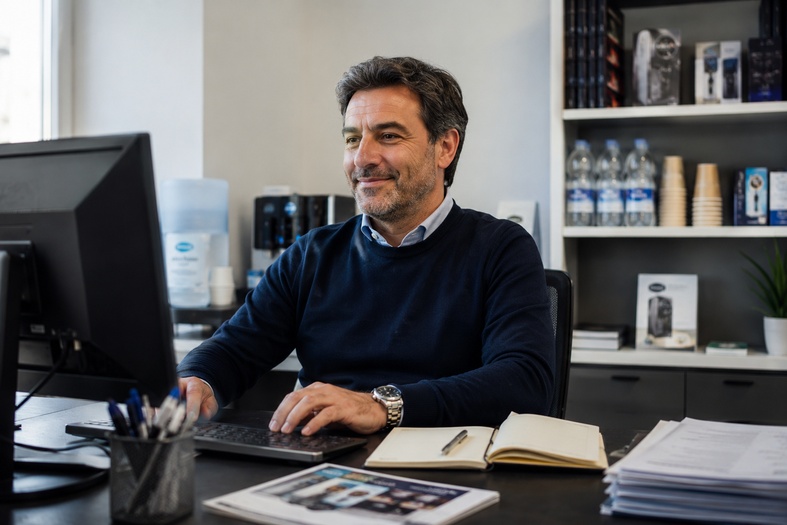 Gestore vending sorridente e sereno alla scrivania davanti al computer