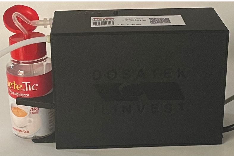 Sistema DOSATEK per distributori automatici con flacone di dolcificante liquido collegato al dispositivo di dosaggio.