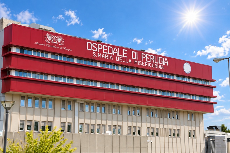 Facciata dell’ospedale Santa Maria della Misericordia di Perugia illuminata dal sole, sotto un cielo azzurro.